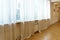 A large spacious unfurnished room with panoramic windows covered with white curtains. A modern fitness room. Wooden parquet on the