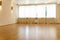 A large spacious unfurnished room with panoramic windows covered with white curtains. A modern fitness room. Wooden parquet on the