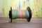 Large spinning wheel bobbin filled with spring colored hand spun yarn