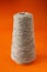 A large spool of beige harsh threads on an orange background