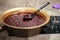 A large spoon with strawberry jam on the background of Strawberry jam cooked in a copper basin.