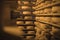 Large stacks of cheese wheels inside a wooden storehouse to age cheese. Rolls of cheese on wooden shelves in a vintage cold