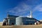 Large Steel Building Agricultural Facility with Grain Bin and Elevator Silos in the Background