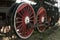 Large steel wheels of old steam locomotive red with white outline