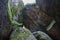 Large stone rocks, boulders covered with green moss are piled on top of each other, from above there is gap of light. Krasnoyarsk