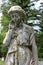 Large stone sculpture of weeping angel covered in moss in cemetery