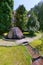 A large stone from which the fountain flows along the background of large juniper trees