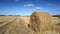 Large straw roll lies on foreground in empty gold field