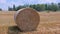 Large straw roll on stubble field in summer.