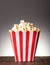 Large striped square box filled with popcorn on gray background.