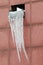 Large stuck together icicle on the exhaust window on a brownish pink tiled wall