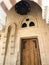 A large sturdy wooden door in a stone arch with a chandelier at the entrance to the Arab Islamic Mosque, a temple