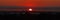 Large sun setting in expansive urban landscape