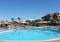 Large swimming pool in the entertainment water park with blue water, sun loungers and parasols