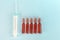 A large syringe and five brown glass ampoules lying on a blue background. Flat lay .The concept of treatment, vaccination, health