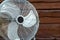 Large tabletop ventilator on the table against the background of a wooden wall. The concept of heat, hot weather, air conditioning