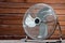 Large tabletop ventilator on the table against the background of a wooden wall. The concept of heat, hot weather, air conditioning