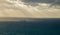 Large tanker ship on smooth ocean with dark storm clouds in the sky. Sunbeams are seen streaking through the clouds.