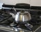 large teapot stainless steel, over the large stove in the restau