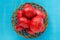 Large tomatoes in a wooden basket on a blue background. Tomatoes background.