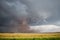 A large tornado fills the air with a huge cloud of dust under a storm cloud.