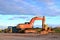 Large tracked excavator and bulldozers on a construction site, background of the sunset.