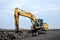 Large tracked excavator with hydraulic hammer breaks asphalt at a construction site on the background sunset. Breaking rock and