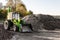 A large tractor with a bucket stands next to a pile of garbage. production waste recycling. Clear blue sky on a sunny day