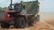 A large tractor with a trailer moves across the field with straw.