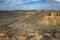 A large truck carries iron ore in the back of a quarry aerial view.