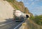 A large truck- tank- carrying fuel on a mountain road, at the entrance to the tunnel. The truck is white. The ridges of the