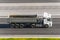 Large truck with trailer bodywork on the highway at a speed that moves along the asphalt, view from top.