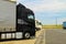 Large trucks of black and white are parked near the road.Delivering or Supply concept. Road train