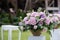 large vase of flowers stands on a white pedestal in the park, a wedding decoration, a festive decor on the nature, pink flowers