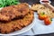 A large Viennese schnitzel on a dark wooden background