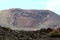 A large volcanoe with dark volcanic rock in the foreground