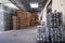 Large warehouse at the factory, winery, bottles of wine in metal baskets ready for transportation, piles of wooden pallets.