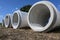 Large water pipes from concrete lying side by side on a construction site to build a drainage sewage system against flooding, copy