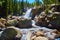 Large waterfall into boulders surrounded by pine trees