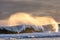 Large wave breaking with spray being lit up by golden sunlight. Long Island New York