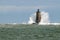 Large Wave Covers Stone Lighthouse Tower in Maine