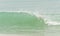 Large wave cresting toward tropical, sandy beach
