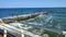 Large wave hitting wooden pier jetty with a lot of splashes on a sunny day.