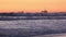 Large waves near an offshore oil drilling rig at sunset slow motion