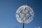 Large white artificial dandelion flower against the blue sky.