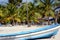 Large white boat close-up on a sandy beach with green palm trees, sunbeds for relaxing and a gazebo on a warm sunny day.