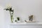 Large white chrysanthemum in a glass transparent vase and two artificial succulents on the table