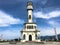 Large white classic lighthouse high in the port against the blue sky