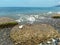 A large white heart-shaped stone on the coastal breakwater. The increasing wave foaming and splashing drops. Summer natural