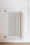 Large white heating radiator with individual adjustment hanging on wall